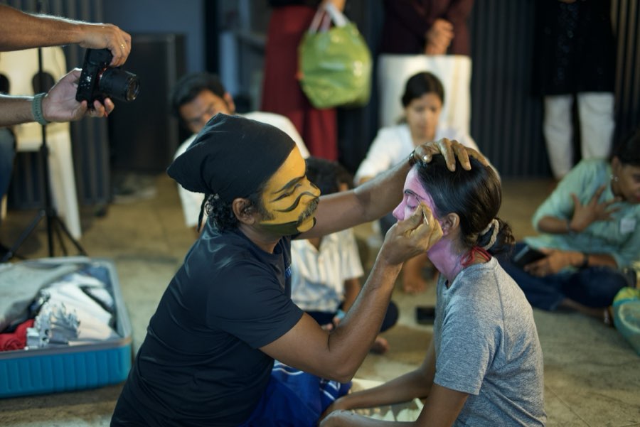 A master artist applying Therukoothu face paint to a participant