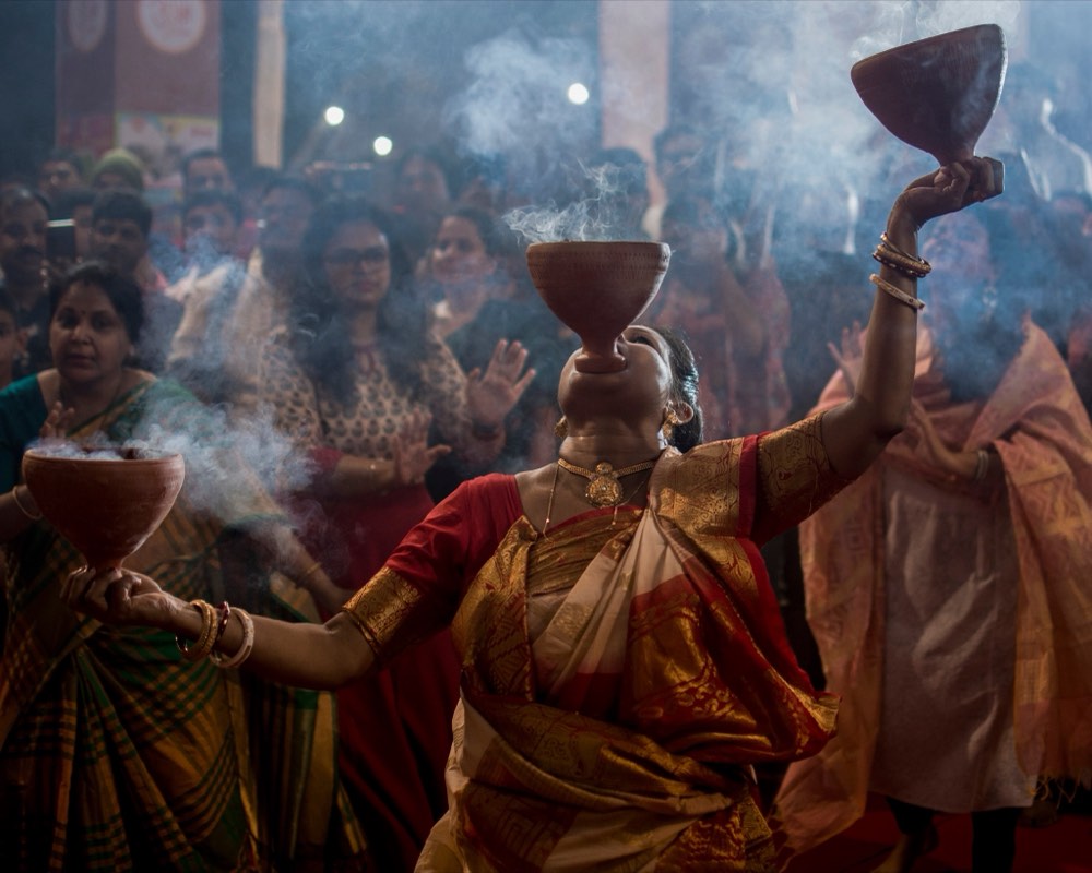 A dancer performing Dhunuchi Naach with a lit incense burner